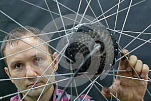 A bicycle mechanic holds a wheel from a bicycle. Bicycle repair. Wheel, spokes and cassette from a mountain bike on a black