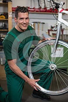 Bicycle mechanic repairing wheel on bike in a workshop