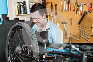 a bicycle mechanic wearing an apron and gloves repairing a mountain bike