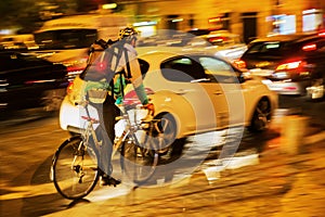 Bicycle messenger in city traffic at night