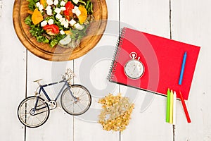bicycle model, salad of fresh vegetables, red notepad, stopwatch