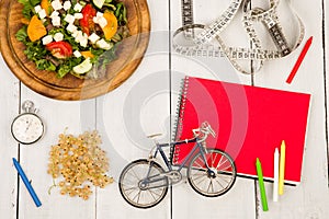bicycle model, salad of fresh vegetables, red notepad, stopwatch