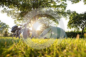 Bicycle with panniers next to a tent at sunset