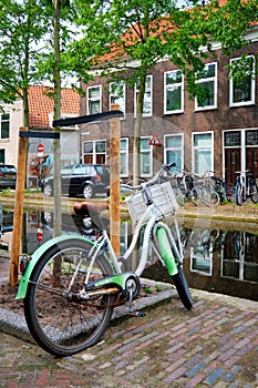 Bicycle parked near the canal in Delft street with old houses. Delft, Netherlands