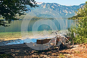 Bicycle parked near the wooden bench on the shore of lake Bohinj