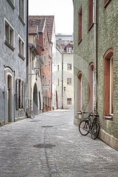 a bicycle parked on an old brick road in a narrow alleyway, Regensburg