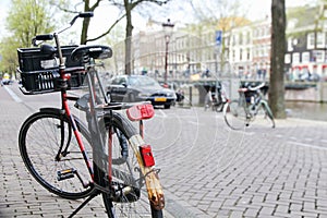 Bicycle parked on the street in the foreground with a typical canal and architecture of Amsterdam, Netherlands