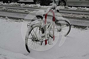 Bicycle parked on the street after a snowfall.