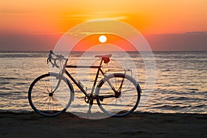 Bicycle parked by tranquil waters under sunset, symbol of relaxation