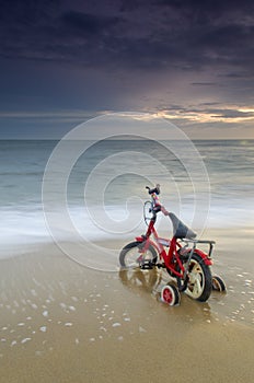 Bicycle parking on beautiful beach on tropical paradise island with sunset in background.