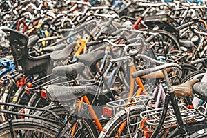 Bicycle parking with lot of bicycles, rainy day, urban iconic transport in Amsterdam.