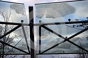 Bicycle parking shelter with glass roof with dotted print. Construction from bent gray tubes into an arc. tempered laminated glass