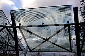 Bicycle parking shelter with glass roof with dotted print. Construction from bent gray tubes into an arc. tempered laminated glass