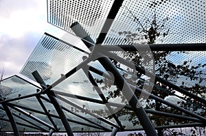 Bicycle parking shelter with glass roof with dotted print. Construction from bent gray tubes into an arc. tempered laminated glass