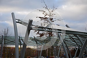 Bicycle parking shelter with glass roof with dotted print. Construction from bent gray tubes into an arc. tempered laminated glass