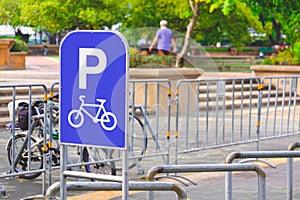 Bicycle parking sign with row of steel bicycle parking space in front of public park, perspective side view