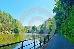 Bicycle path along the lake and green forest.