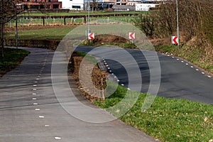 Bicycle path in both directions next to a country road with dangerous curve marking