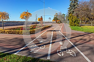 Bicycle path in the city garden along the river embankment on a sunny autumn day