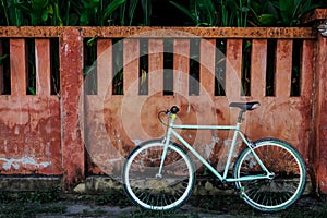 Bicycle and red cement wall on background.