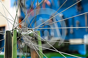 Bicycle repair. The front wheel is on a stand on the background of the board with tools. Rim and spokes close-up. Mechanic levels