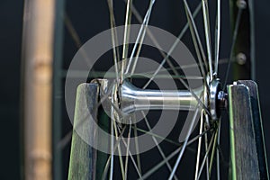 Bicycle repair. The front wheel is on a stand on a black background. Rim and spokes close-up. Mechanic levels the wheel in the