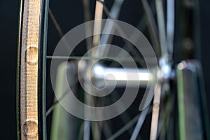 Bicycle repair. The front wheel is on a stand on a black background. Rim and spokes close-up. Mechanic levels the wheel in the