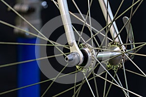 Bicycle repair. The front wheel is on a stand on a black background. Rim and spokes close-up. Mechanic levels the wheel in the