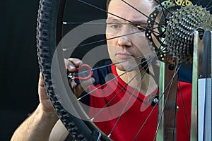 Bicycle repair. Rear wheel and tire closeup. Mechanic repairing spokes of the rear wheel of a mountain bike. Bike mechanic in the