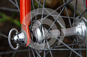 Bicycle repair. Wheel and shiny axle of chrome steel of an old road bike closeup. Retro bike. Red iron fork. Quick Release
