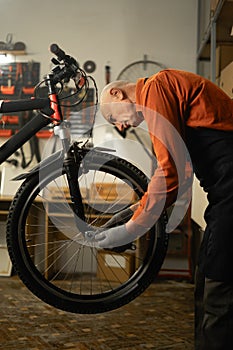 Bicycle repair in workshop. Repairman. Old male mechanic working in bicycle repair shop, repairing bike in his garage