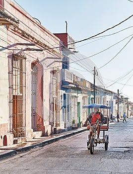 Bicycle rickshaw riding on asphalt street in colonial old town Trinidad, Cuba.