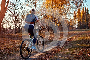 Bicycle ride workout in autumn park. Young woman biker riding a bike in fall forest. Healthy training
