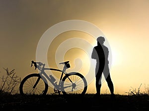 Bicycle rider stand on the hill watching the sunlight and relax