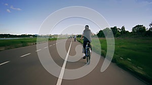 Unknown bicycle riders move along the park bike path