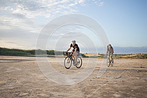 Bicycle riders ride outdoors on the fields near lake
