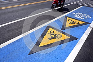 Bicycle road sign, arrow with bike lane text and blurred motion of motorcycle on asphalt road