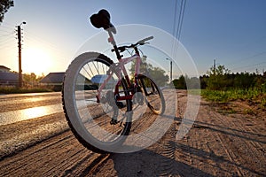 Bicycle silhouette at the sunrise dirt road in the countryside. Idea and concept of physical activity and healthy