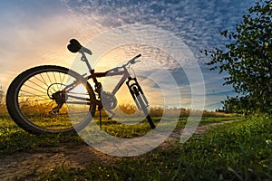 Bicycle silhouette at the sunset dirt road in the countryside. Idea and concept of physical activity and healthy