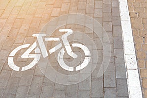 Bicycle slab paved lane at pedestrian walking area. Bike symbol painted with white paint on grey paved road. Cycling friendly