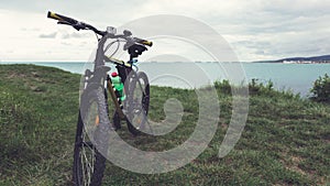 A bicycle stands on a green lawn of the sea coast with a view of the mountain range concept of active recreation and healthy lifes