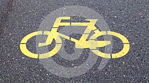 Bicycle symbol representing a path for bicycles. Yellow painted sign for bicycles on the asphalt. Flat lay, top view