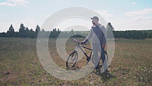 The Bicycle Traveler Stands in the Field, the Sun Comes Out from the Cloud. Free Traveler Travels by Bike. Adventure and