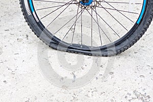 Bicycle wheel with flat tyre on the concrete road.