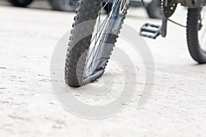 Bicycle wheel with flat tyre on the concrete road.