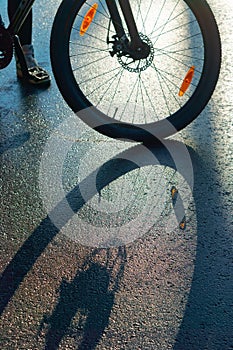 A Bicycle wheel on the pavement, shadow of Bicycle on the road