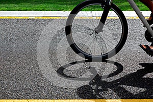 A bicycle wheel rides along an asphalt road.