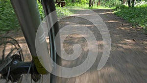 Bicycle wheel spokes ride along ground path in forest