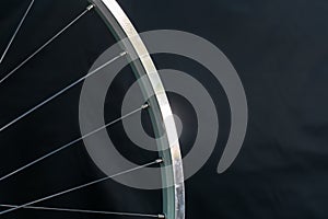 A bicycle wheel without a tire on a black background in the workshop. Bicycle repair. Rim and spokes of a mountain bike wheel