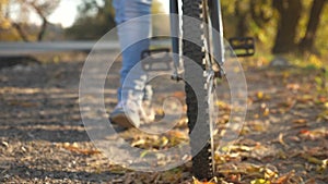 Bicycle wheel with treads, close-up. legs of girl go on road and rolls the bike.